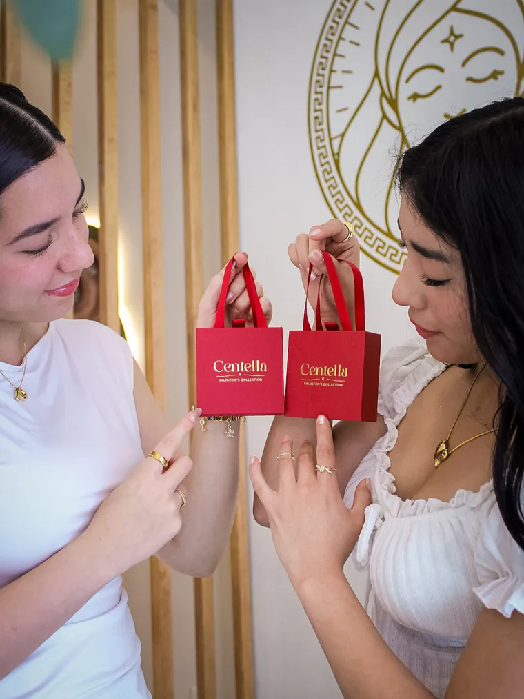 Colección San Valentín: empaques rojos y joyería dorada en vitrina.